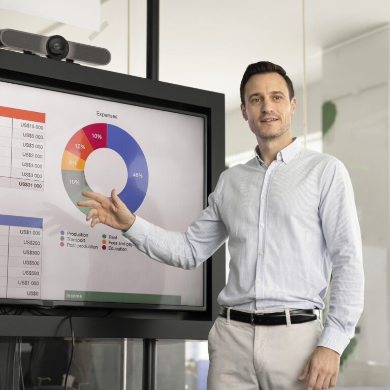 Ein Mann präsentiert ein Diagramm auf einem Bildschirm vor einer Gruppe von Zuhörern.