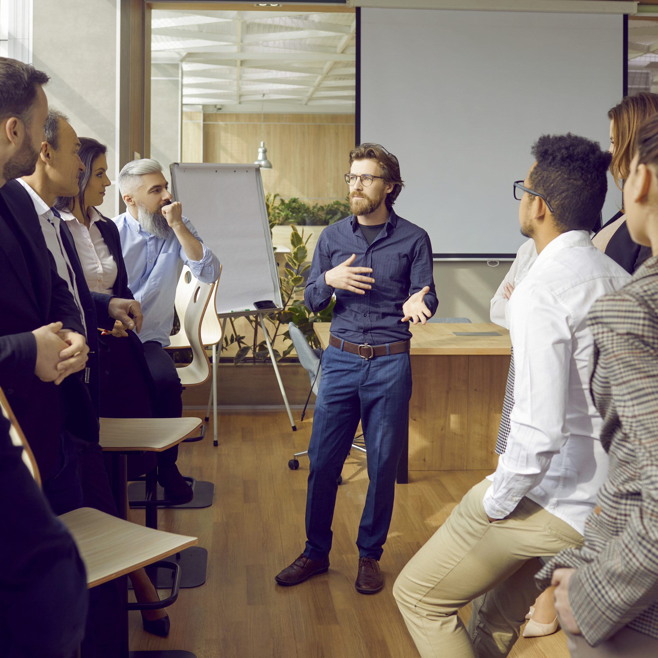 Ein Mann leitet ein Training mit einer Gruppe von Menschen, die aufmerksam zuhören und teilnehmen.