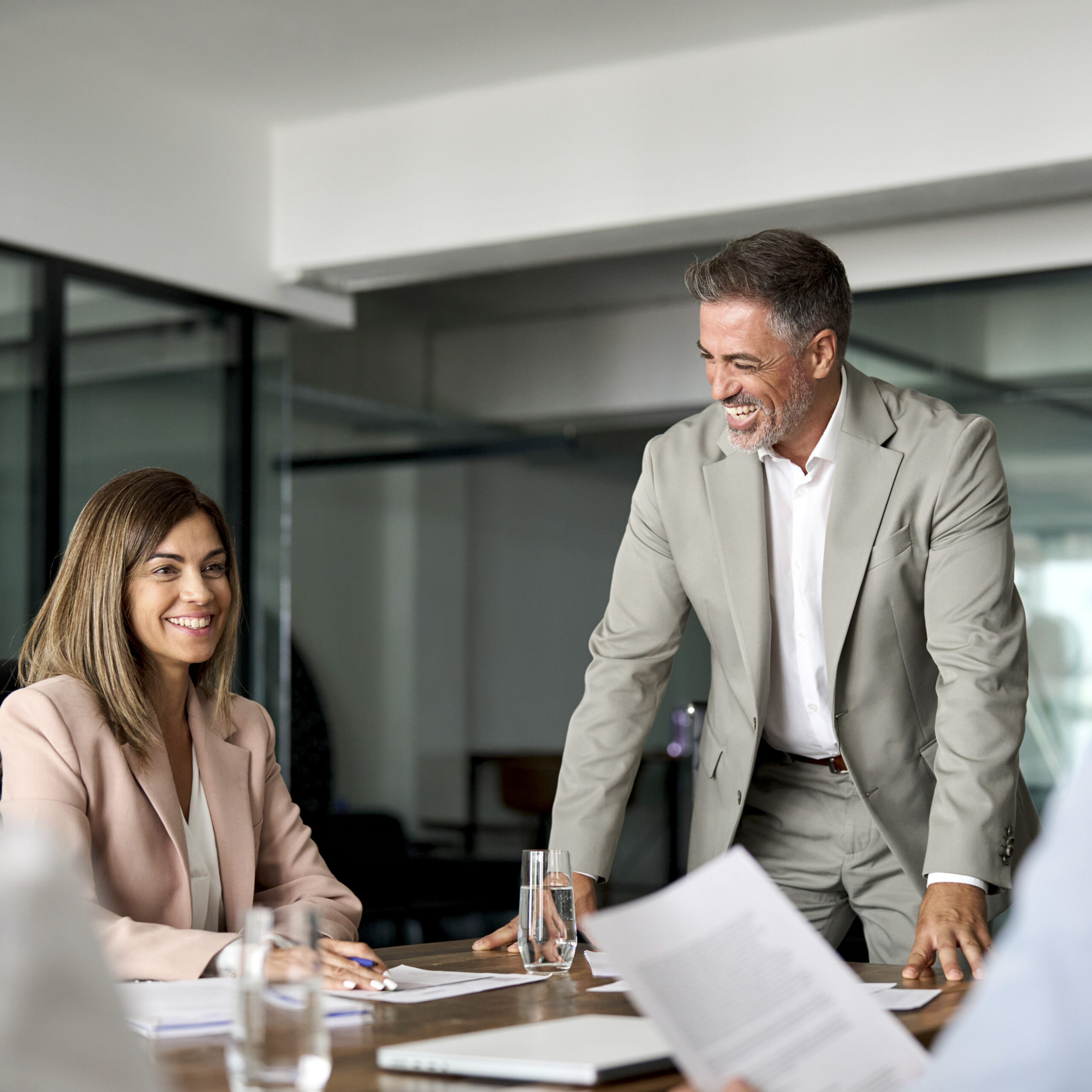 Ein Mann und eine Frau im Gespräch in einem modernen Konferenzraum, beide im Business-Look.